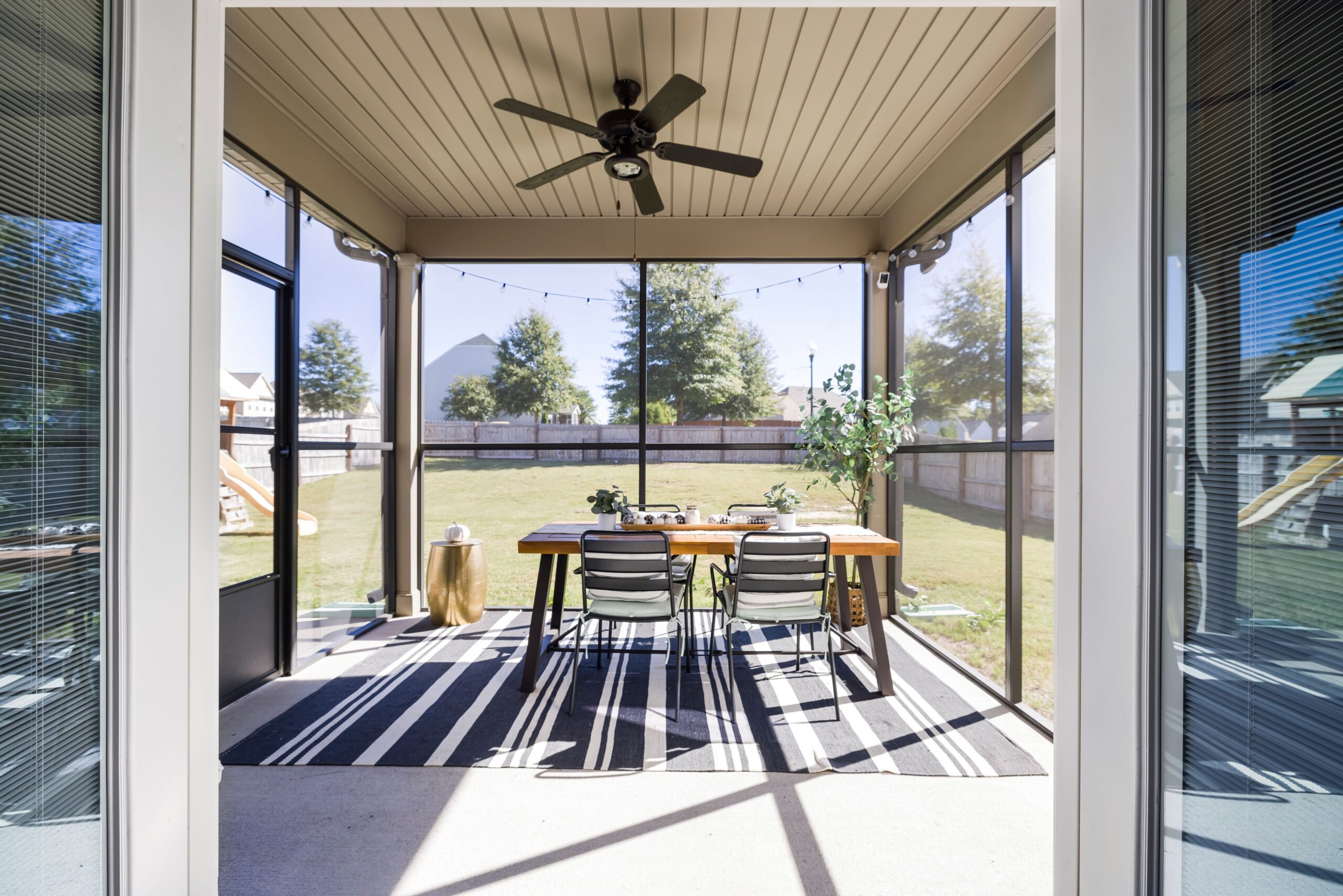 A bright and inviting terrace with dining table and chairs, overlooking a sunny garden.